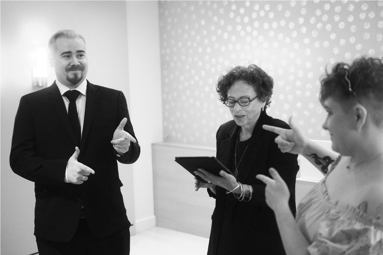 Wedding couple, Rene and Rachel with wedding officiant SandraLaya Ruch pointing at each other during their wedding ceremony